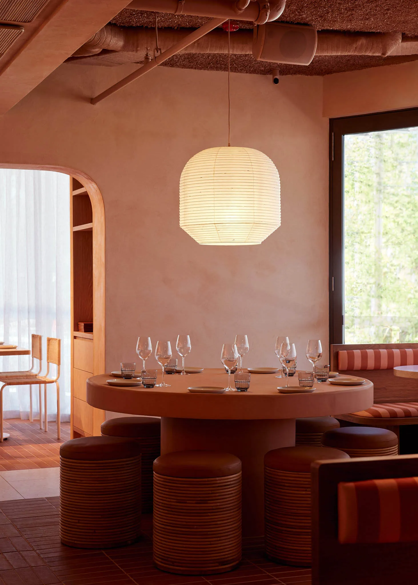 Warm and inviting restaurant interior with a round table, chairs, and wood elements, featuring wine glasses and a cozy atmosphere