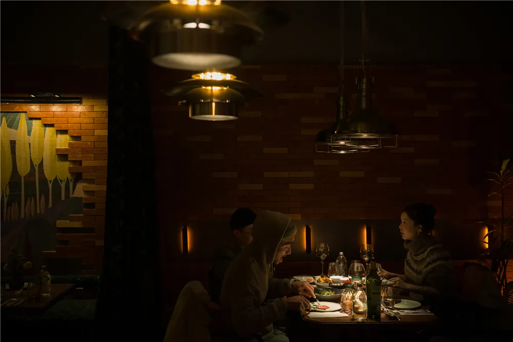 A group of people dining together in a warm and inviting Asian restaurant setting with a dining table, chairs, wine glasses, and various tableware