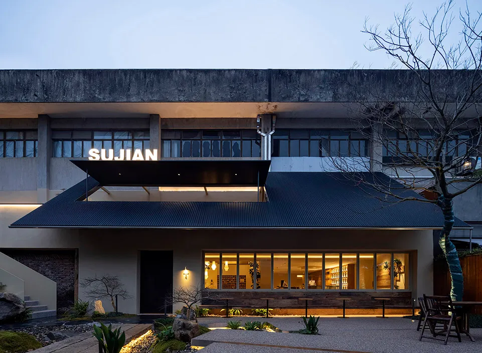 Modern building with a large roof overhang, featuring a mix of concrete, wood, and metal materials, with natural light entering through several windows