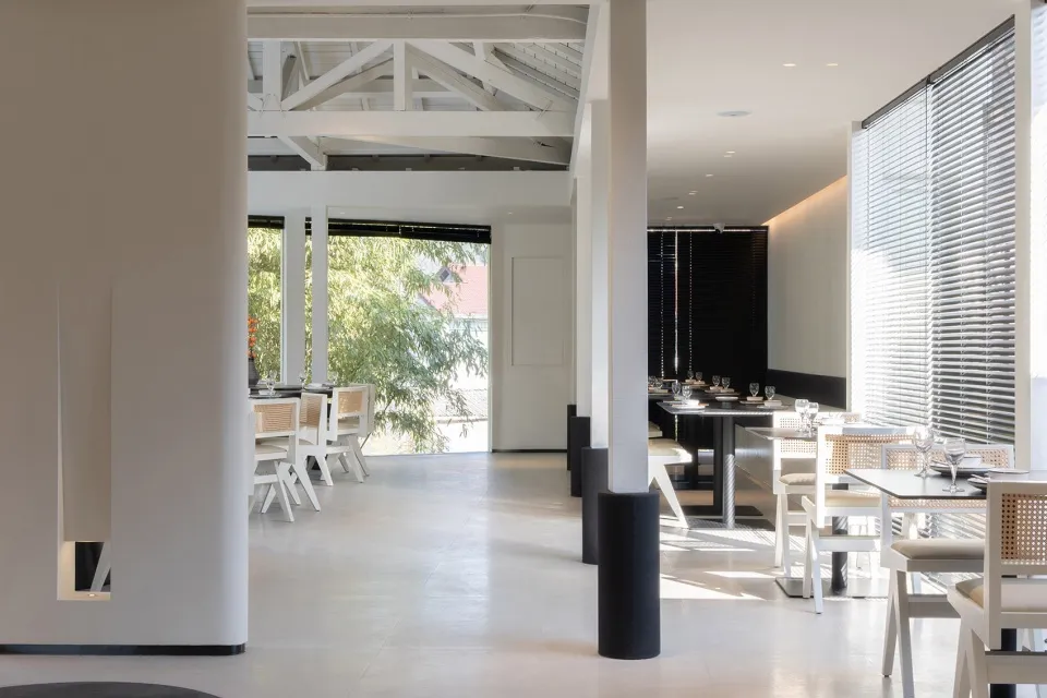 A modern restaurant with a clean and inviting dining area featuring multiple tables and chairs, with wine glasses on some tables, set for service