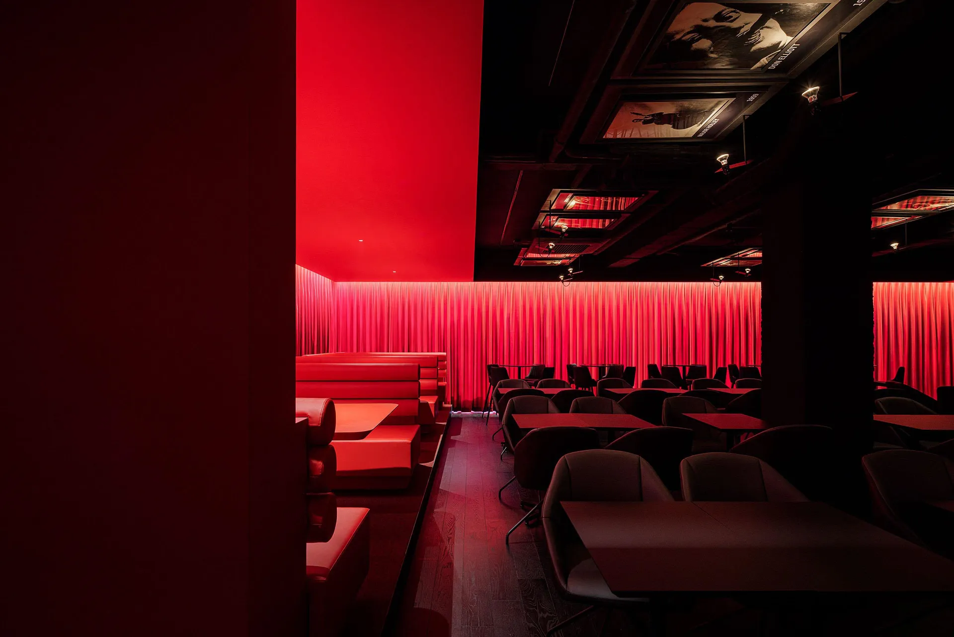 A warm and inviting event space with red walls, orange chairs, and multiple dining tables with seating options