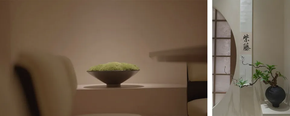 A black ceramic bowl filled with green substance sits on a wooden table in a simple setting