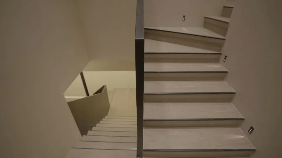 A photo of a staircase with a black railing in an indoor setting