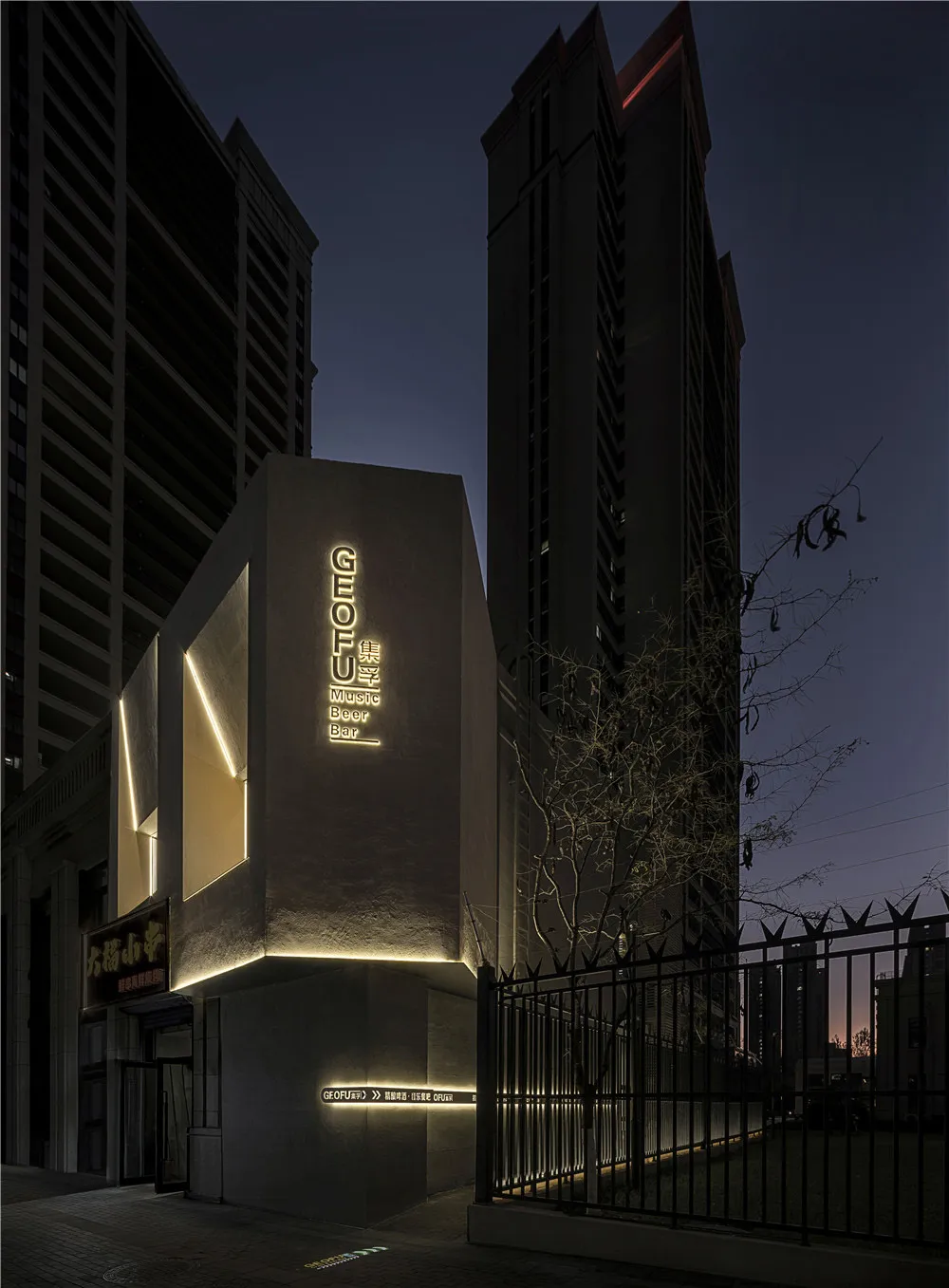 一座具備混凝土結構與醒目招牌的現代建築，襯托在暗色夜空下