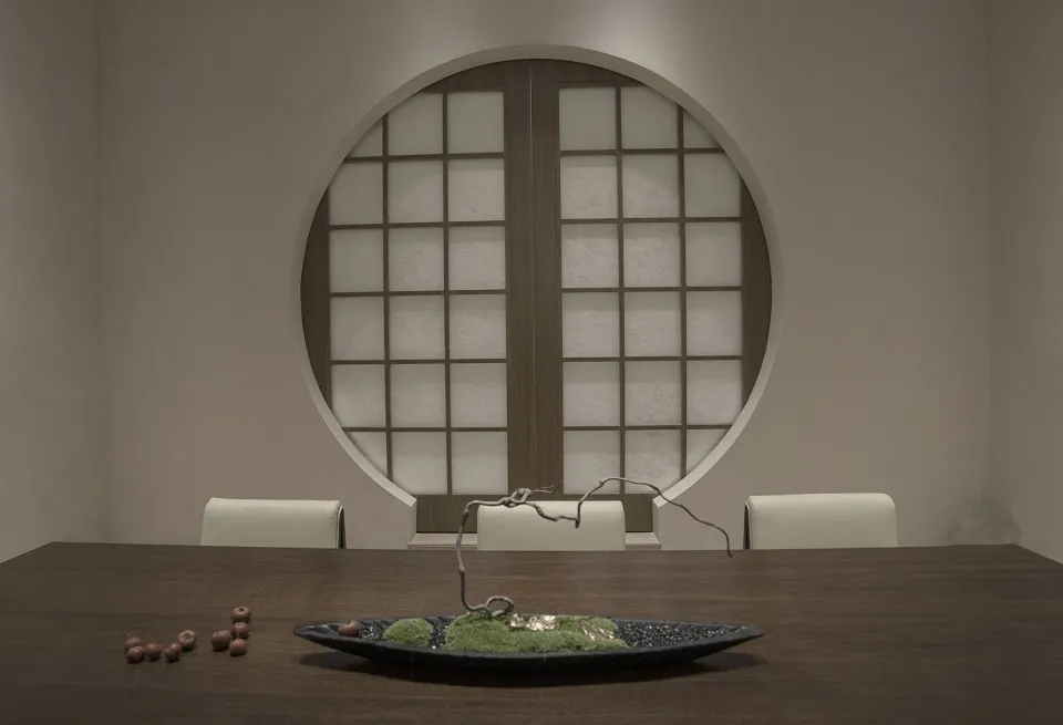 Elegant dining space with a wooden table, chairs, and a bowl on the table, surrounded by simplicity and harmony