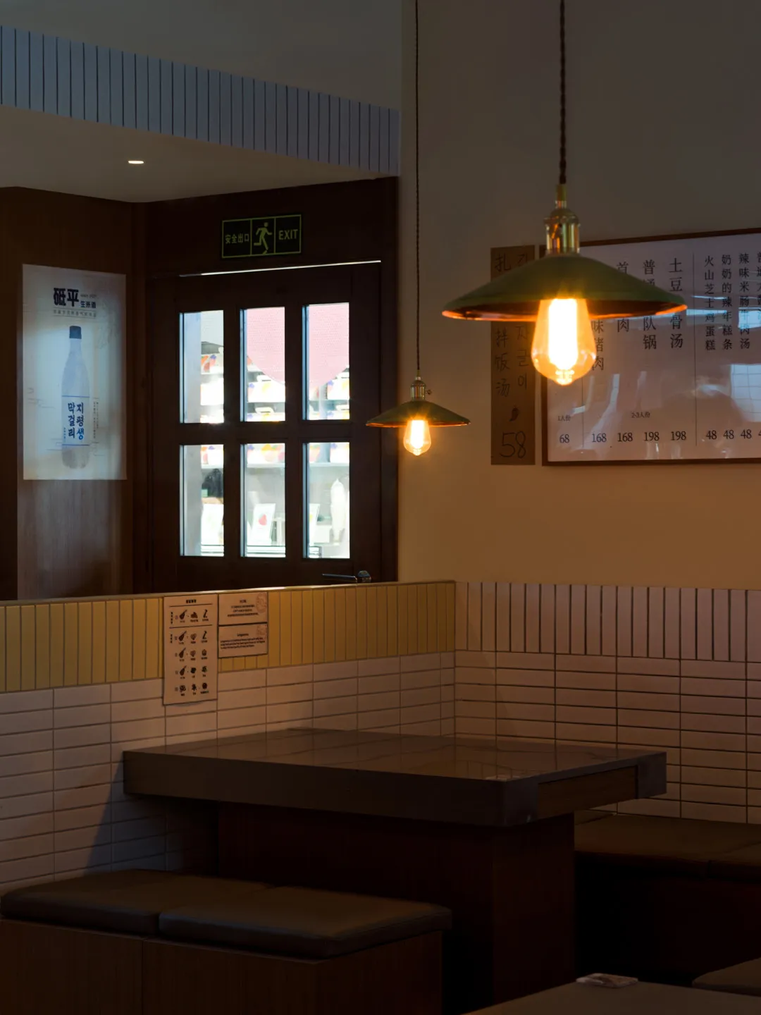 溫馨亞洲餐廳內部，設有長餐桌、馬賽克磚牆與懸吊燈光