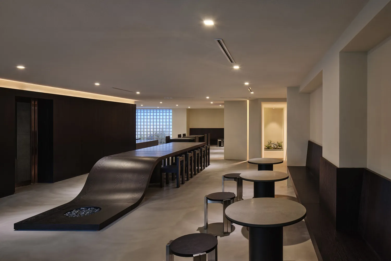 Modern bar area with a long counter and stools, surrounded by dining tables and a modern atmosphere