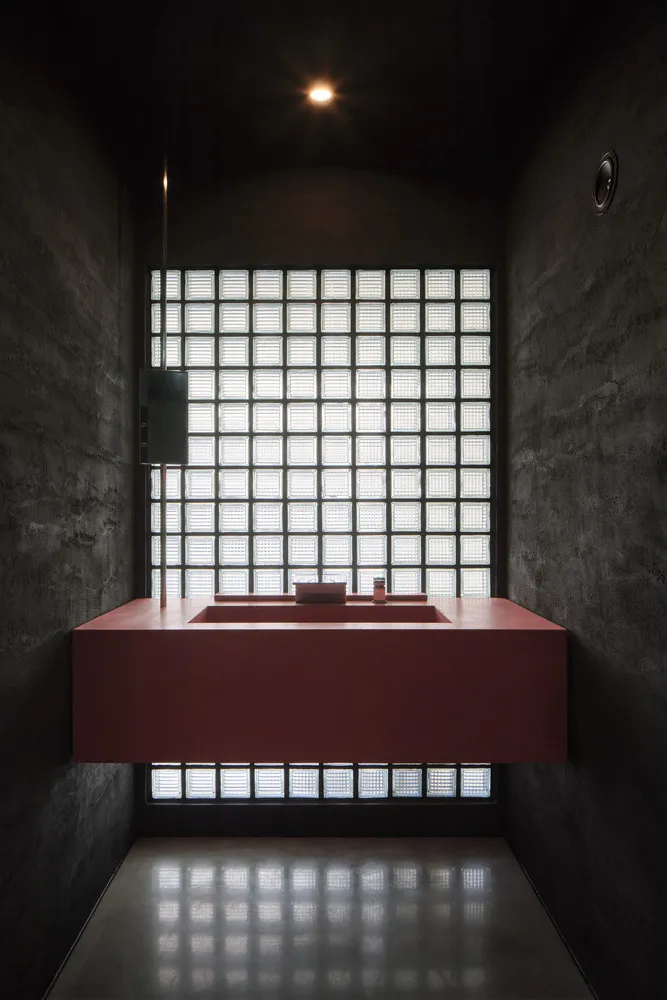 A bathroom with two sinks, one with a mirror, a toilet, and checkered-patterned walls, set in a well-lit and inviting space
