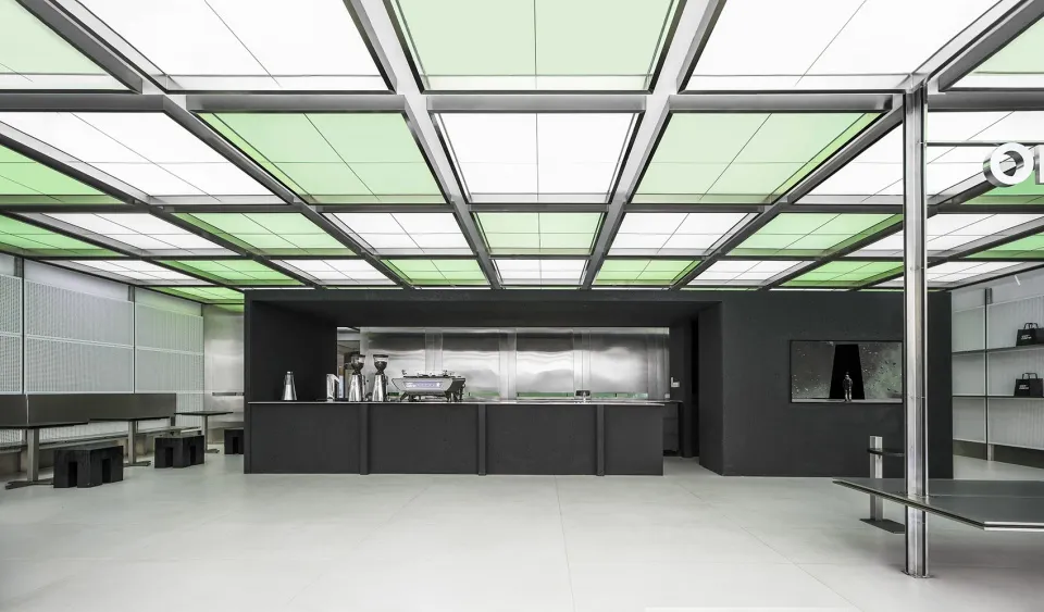 Industrial kitchen with a black countertop, two sinks, and modern appliances, set against a large window