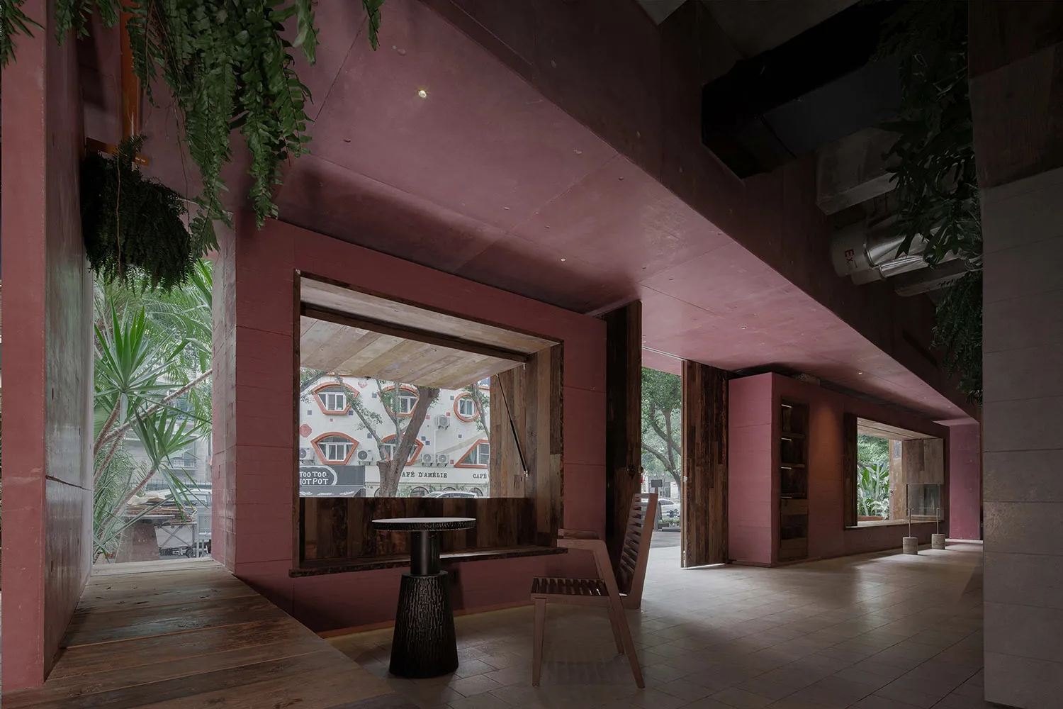 A warm and inviting cafe interior with a pink accent wall, wooden floors, and a dining table, featuring two chairs and a vase for ambiance