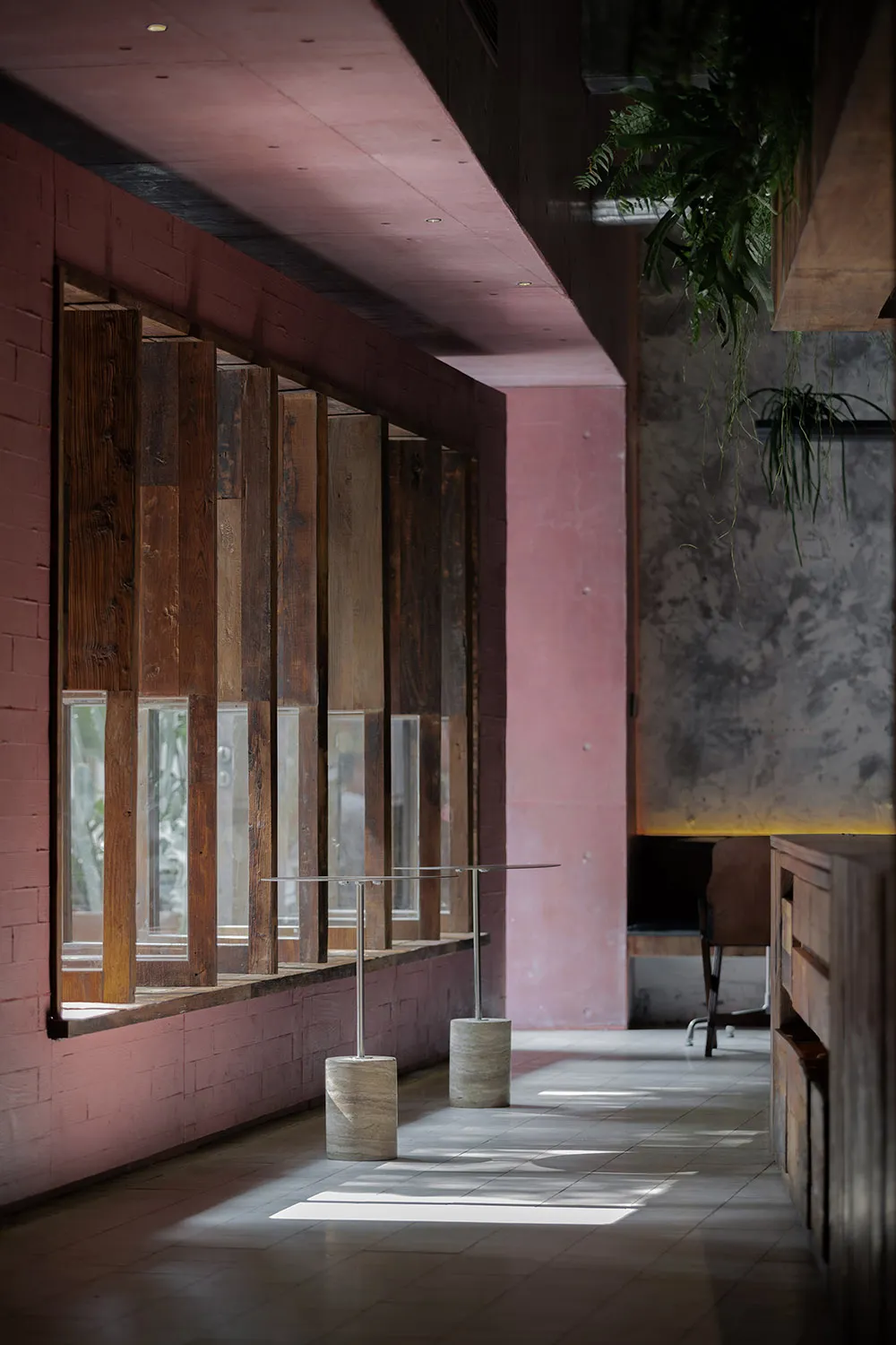 Modern interior space with a large window in a brick wall, featuring multiple panes of glass and a minimalist aesthetic, with two chairs and a potted plant