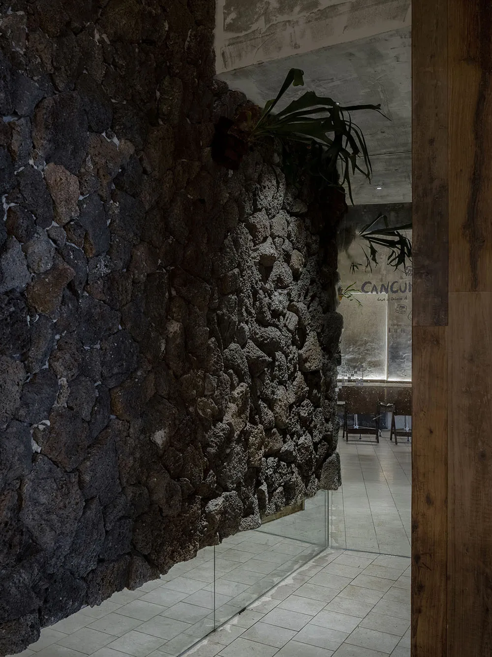 Cozy living space with a stone wall, two chairs, and three potted plants, creating a warm and inviting atmosphere