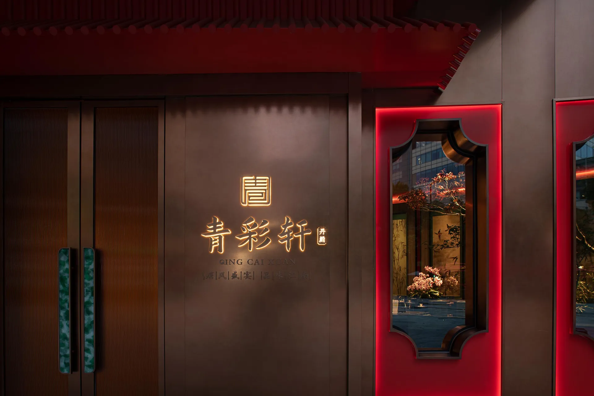 A modern Asian restaurant with red walls, large windows, and potted plants, featuring decorative elements and a welcoming atmosphere