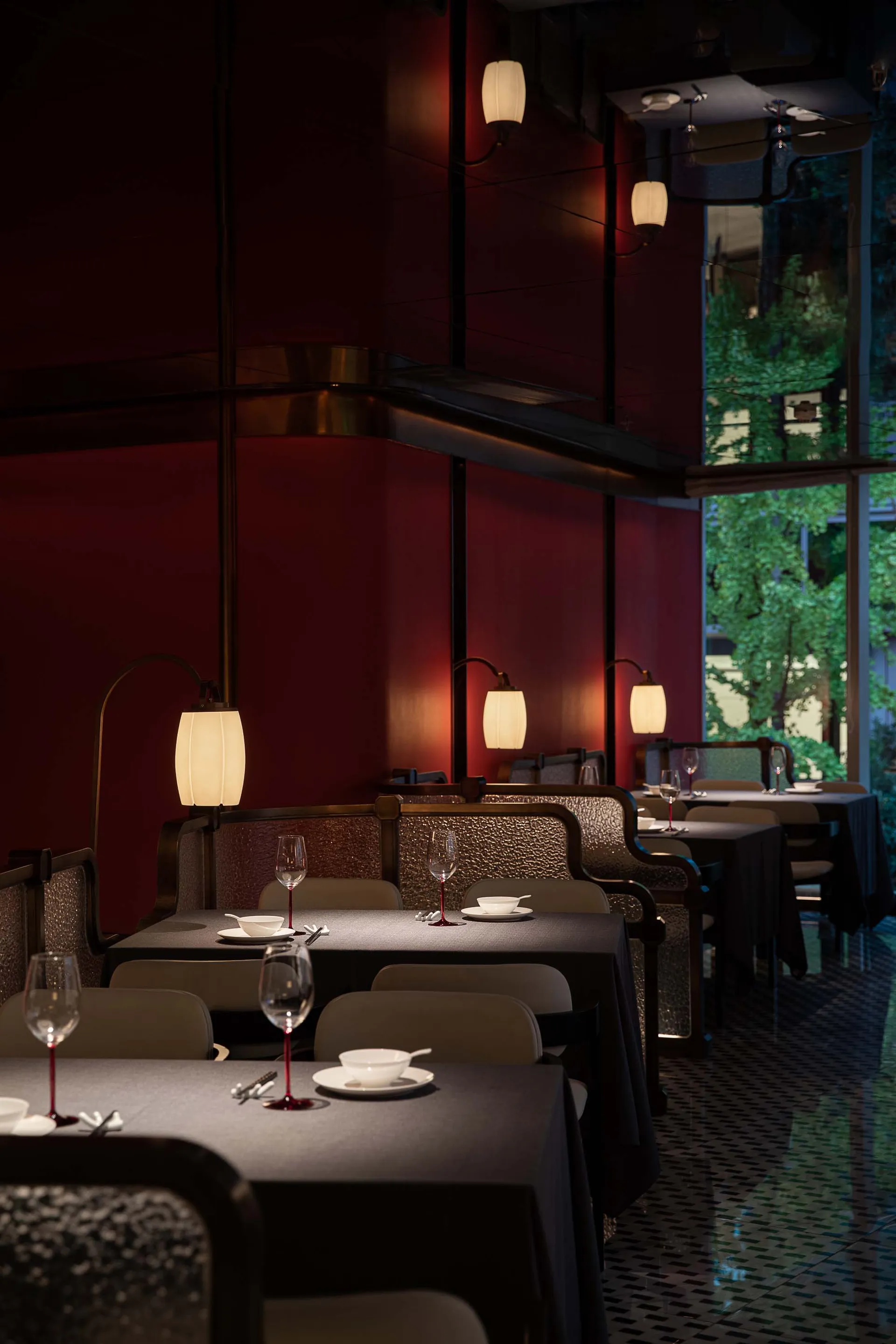 Elegant restaurant interior with red walls, black tables, and wine glasses, creating a sophisticated atmosphere