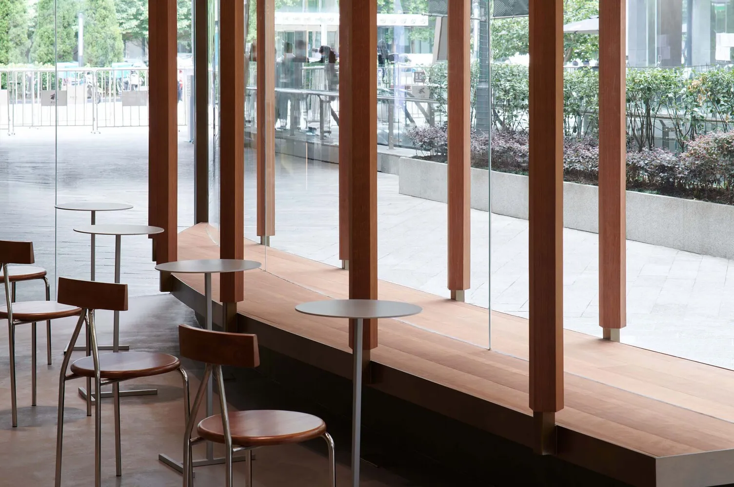 Modern dining space with wooden floors, glass walls, and several chairs with dining tables