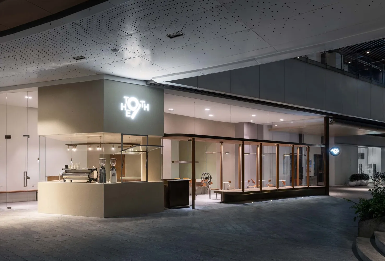 Open modern restaurant with natural light, white walls, wooden floors, and seating areas