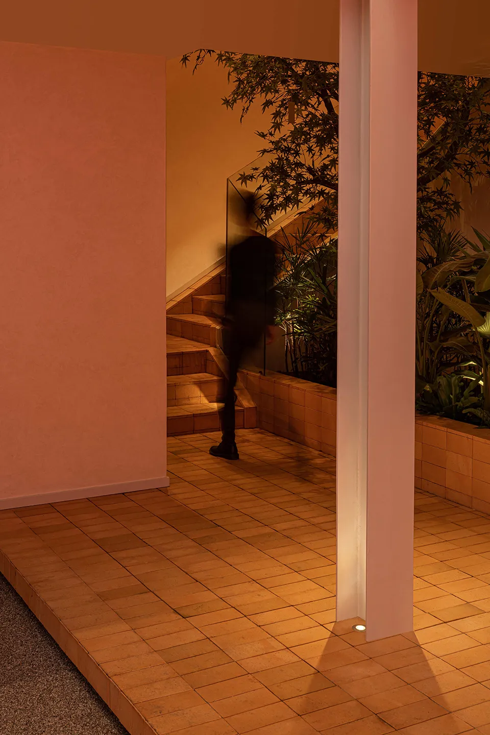 A calm residential staircase with wooden steps and a brown tint, featuring a person at the bottom