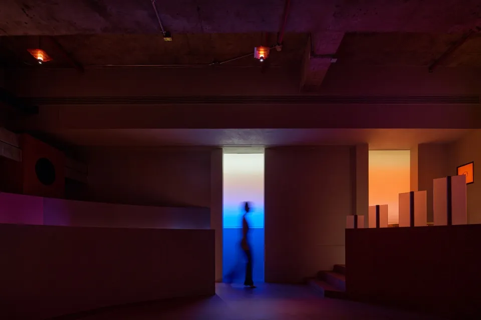 A person walks down a hallway with a concrete floor, creating a sense of depth and atmosphere