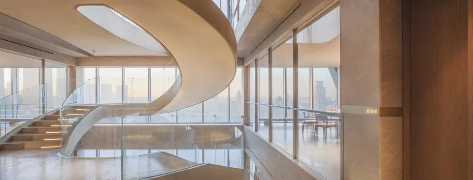 Modern open building with a spiral glass staircase, minimalist design, and natural light from windows or skylights
