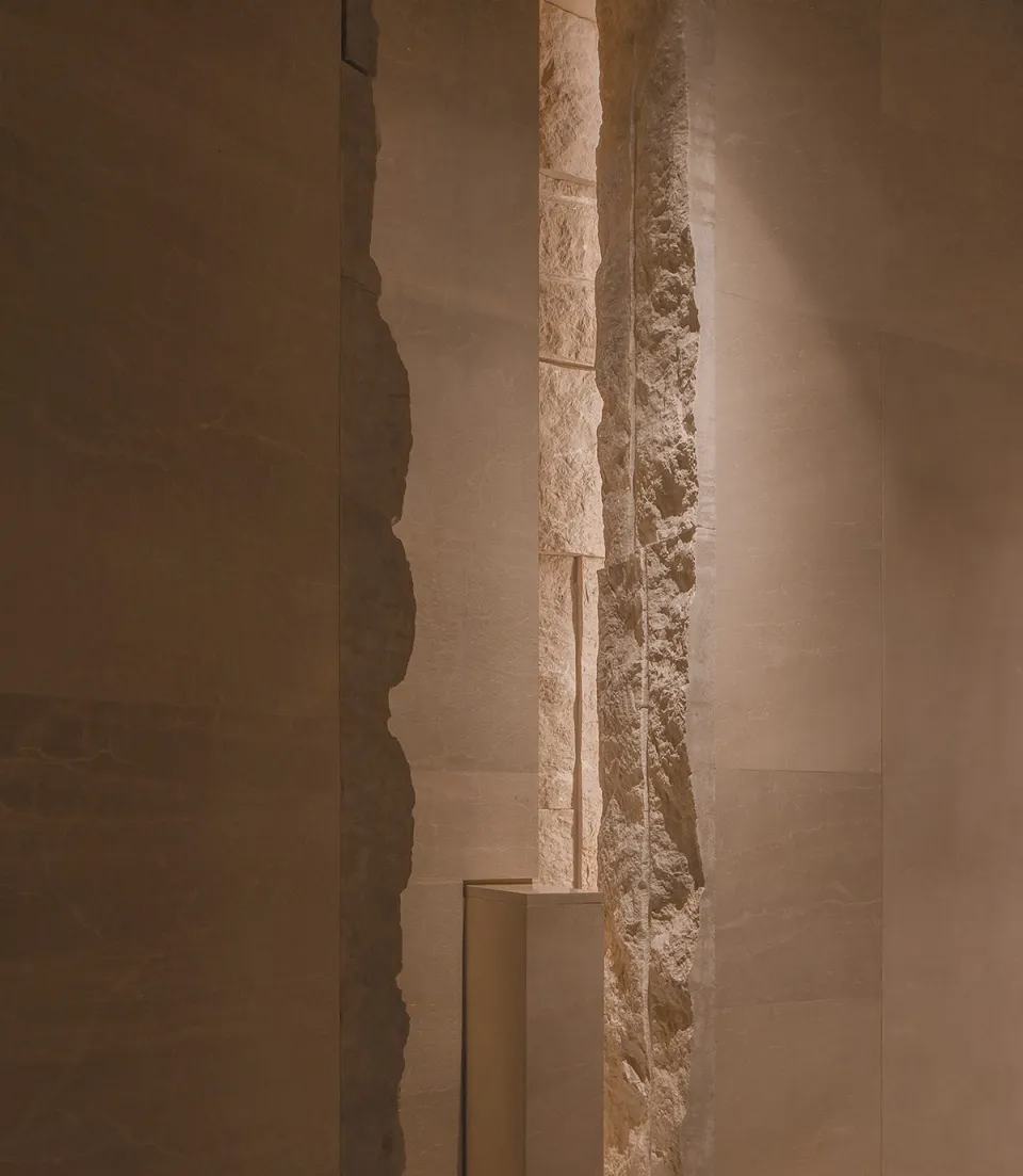 Dark interior space with a stone wall and a concrete wall, featuring a textured and smooth surface respectively