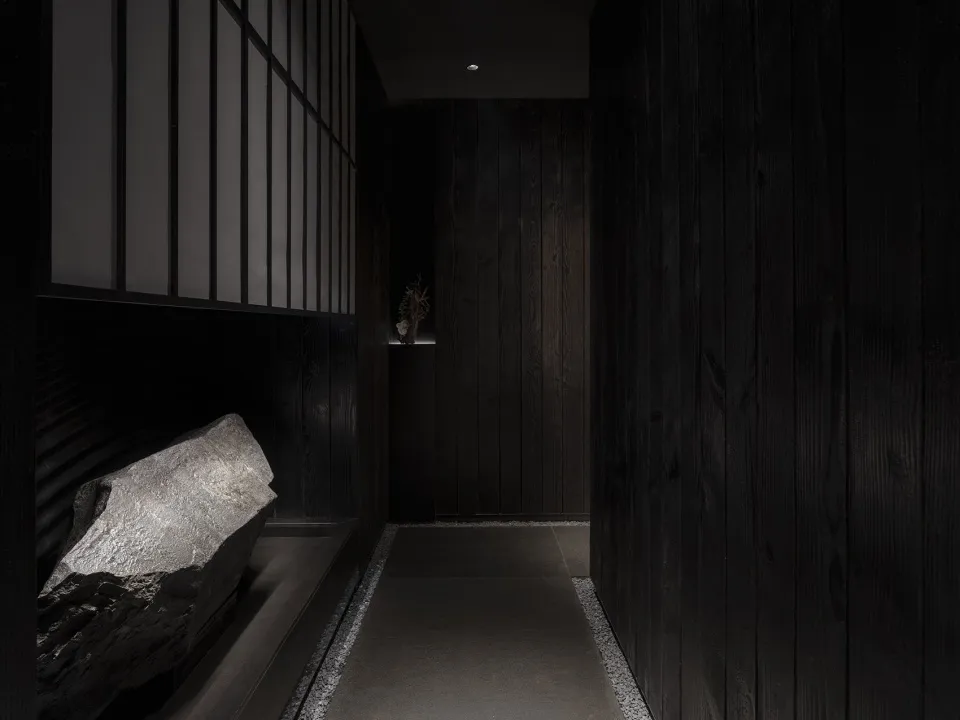 Narrow hallway with dark wood walls and flooring, two doors, and a cozy atmosphere