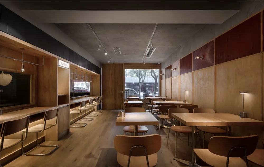 Modern restaurant interior with wooden floors, tables, and chairs, creating a warm and inviting atmosphere