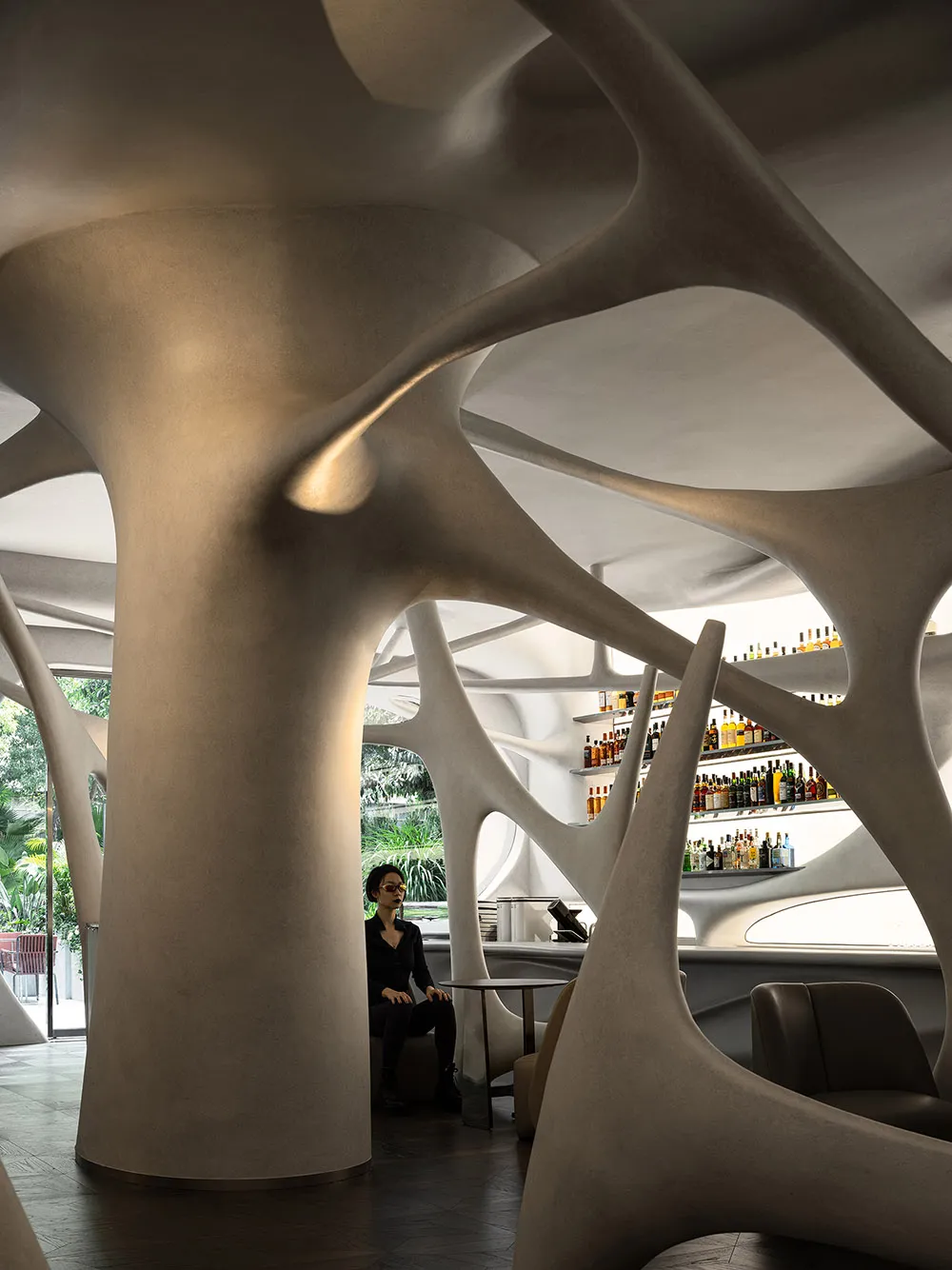 A modern bar area with a curved wall, bottles, and seating for patrons