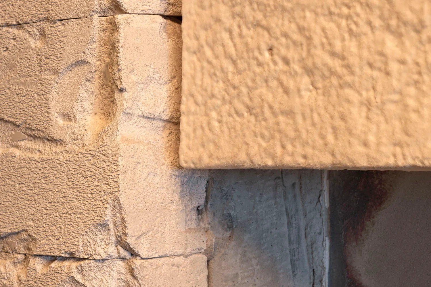 A traditional building exterior featuring a stone wall with a brick pattern, warm lighting highlighting the textures and details of the stone and brick
