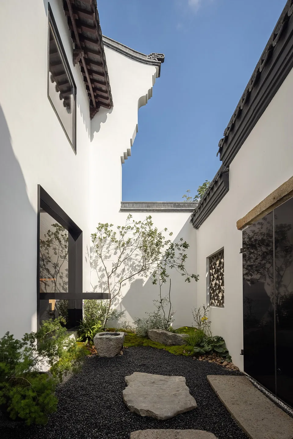 寧靜庭院搭配白色建築，點綴植物、岩石與裝飾花瓶，營造平和氛圍