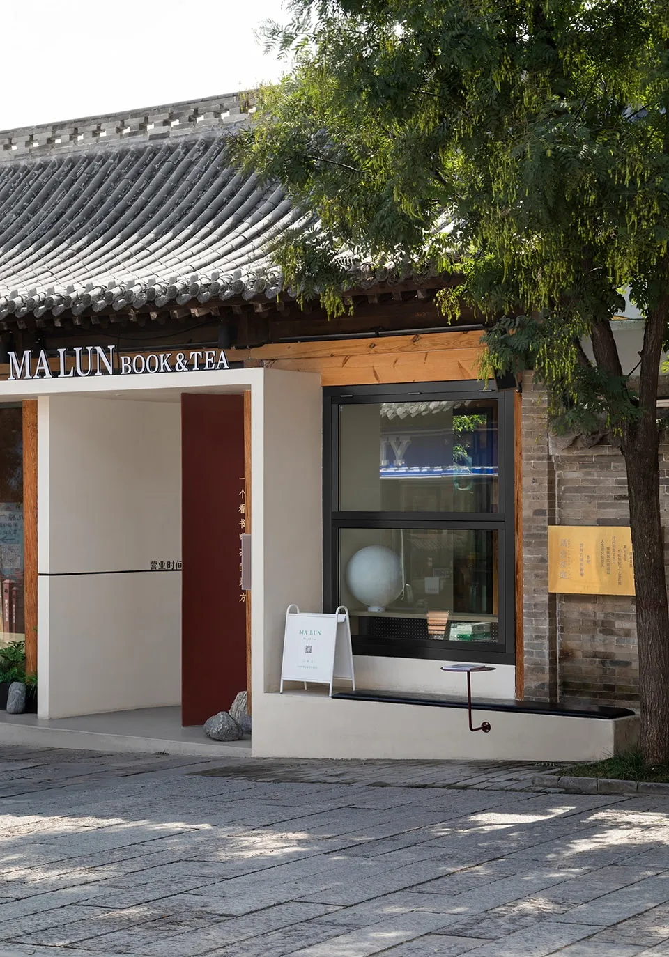 亞洲風格住宅，紅色大門與白色牆面，周圍環繞兩棵樹木及帶招牌的窗戶