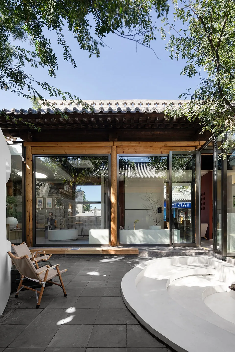 木質外觀的現代極簡住宅，寬敞開放客廳，中央白色浴缸，周圍配有兩把椅子與自然光線