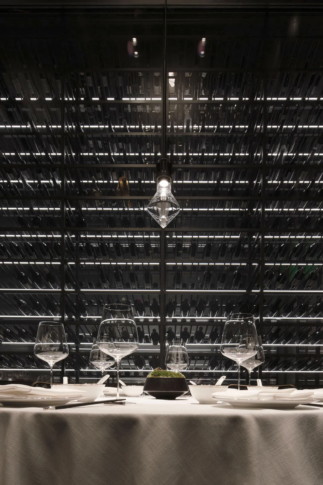 A well-lit dining area with a table surrounded by wine glasses and bottles, set in a modern restaurant or event space