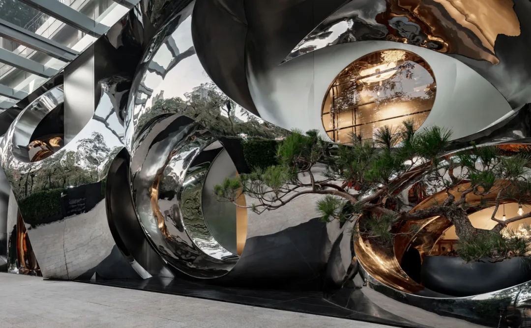 A modern interior space with a black and white color scheme, featuring a large tree in the center surrounded by various rooms and industrial elements
