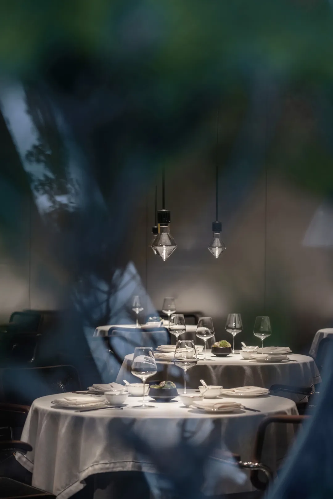 A luxurious dining area with a large table set for a special occasion, featuring wine glasses, bowls, cups, and utensils, surrounded by comfortable chairs