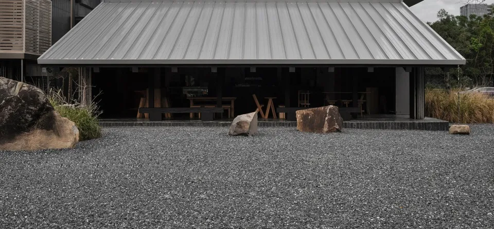 碎石地面上的戶外區域，設有兩塊大岩石、座椅與餐桌，營造休閒舒適的氛圍