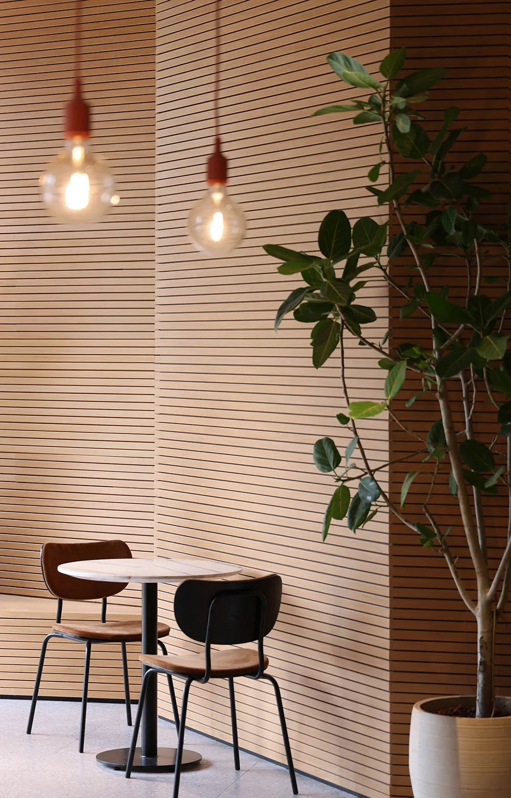 Cozy dining area with wooden paneling, two chairs, and a small table, lit by three lights
