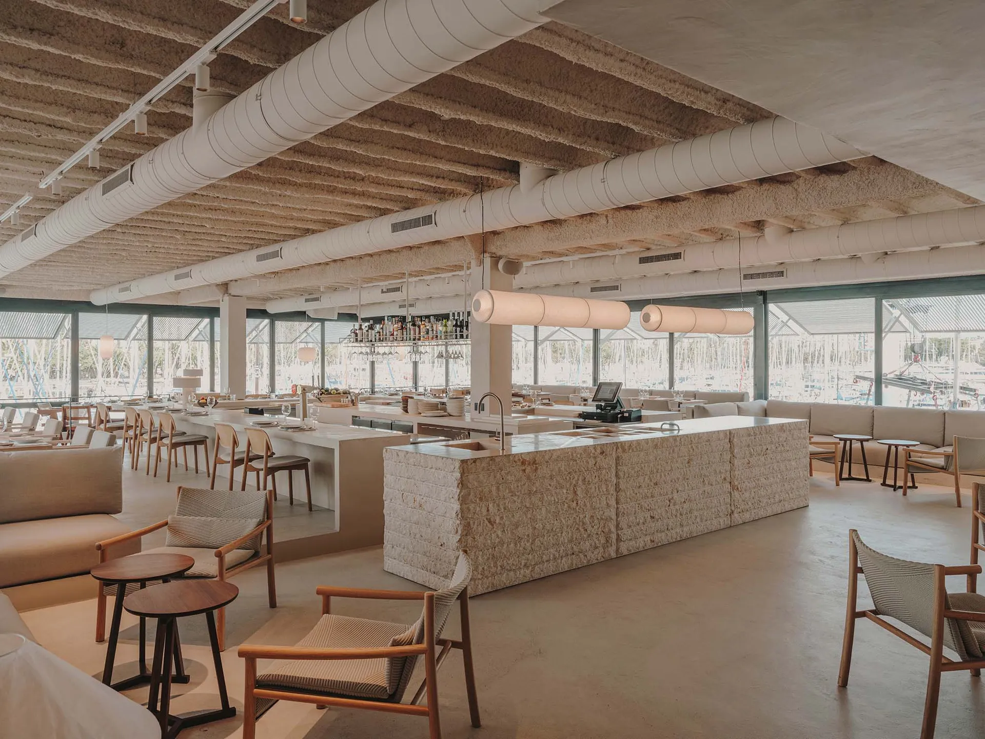 Inviting restaurant interior with a wooden bar, dining tables, and bottles on display, featuring a relaxed atmosphere for socializing and dining