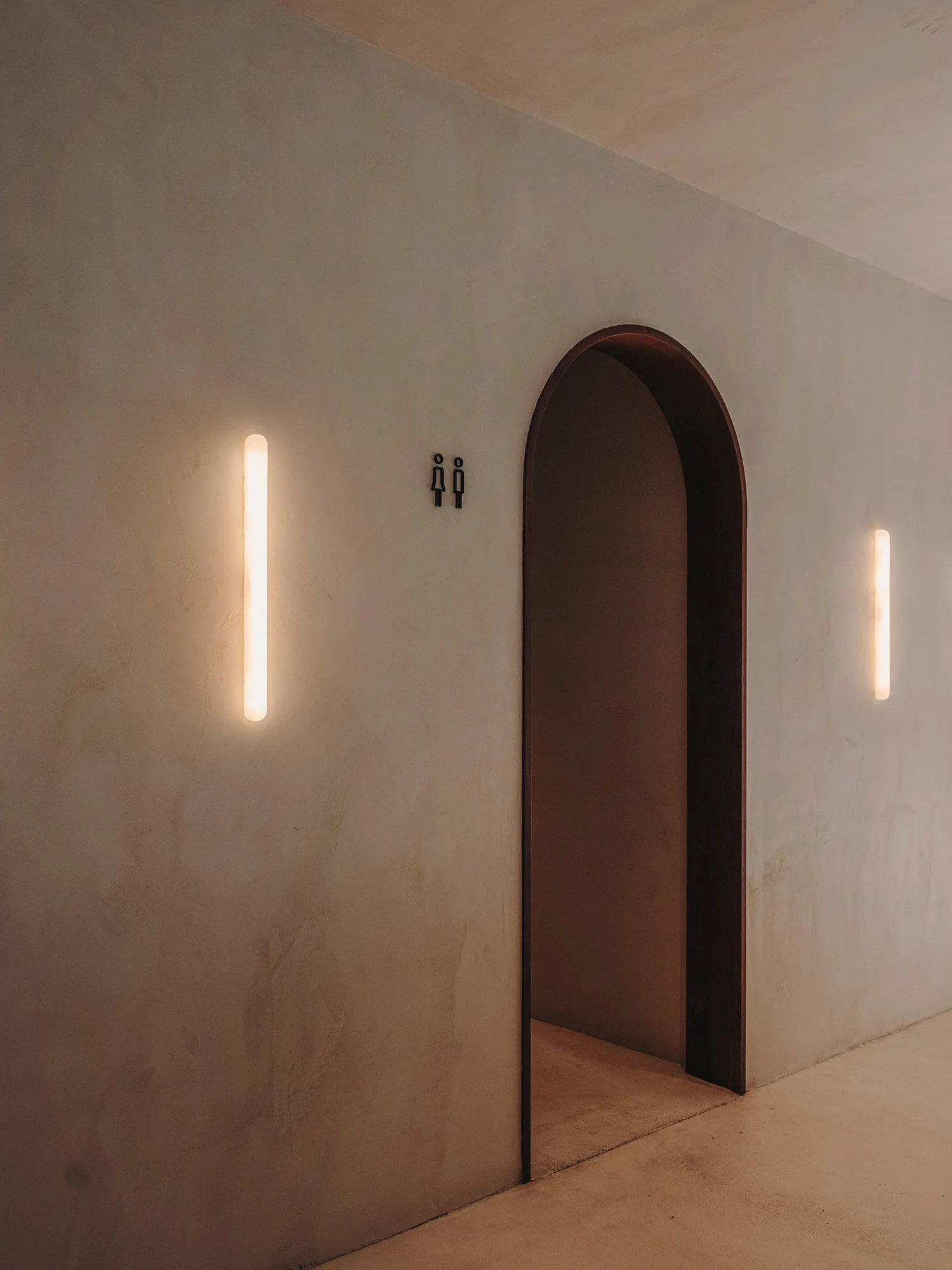 Empty hallway with a wooden doorframe, lit by two lights on either side