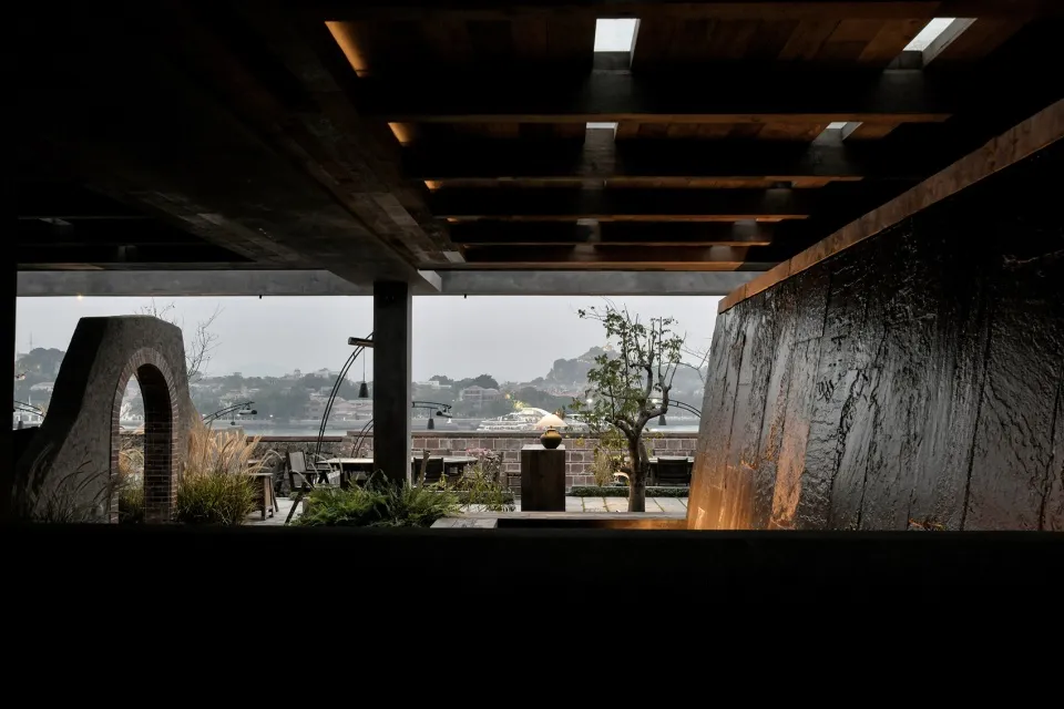 A house with a patio area and large window, surrounded by potted plants, creating a relaxing and inviting atmosphere