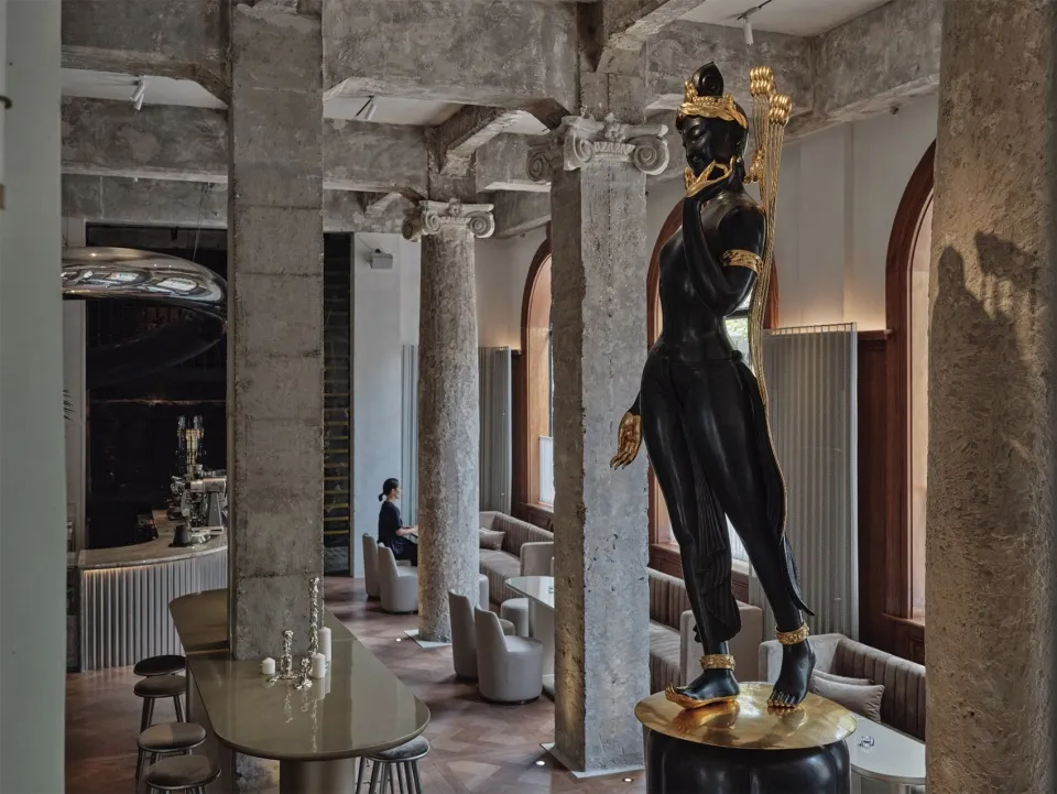 一座華麗的餐廳，腳踏上擺放精緻雕像，周圍環繞餐椅與餐桌，呈現奢華的室內設計風格