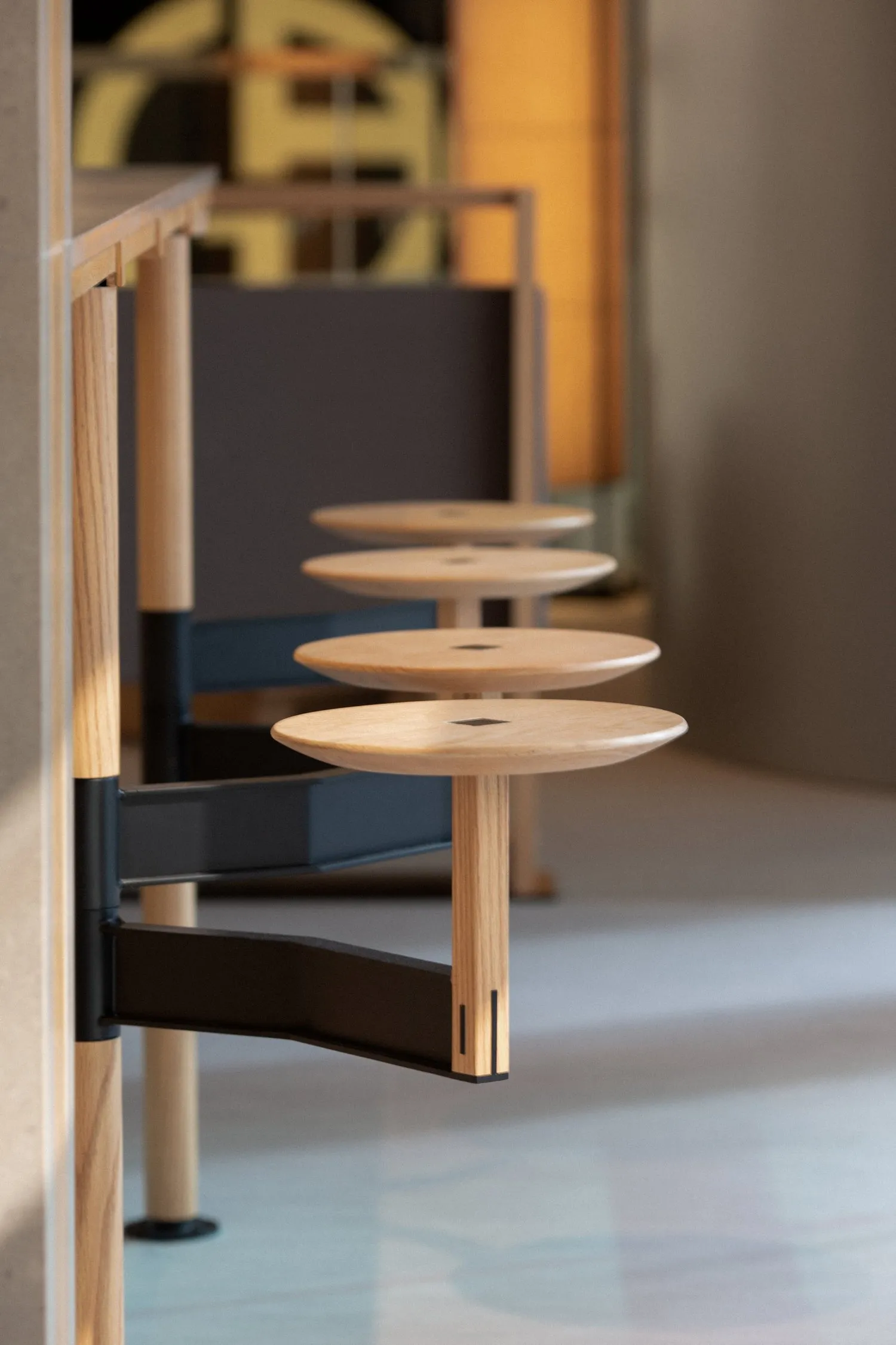 A minimalist study with a wooden bookshelf featuring three empty shelves with black frames