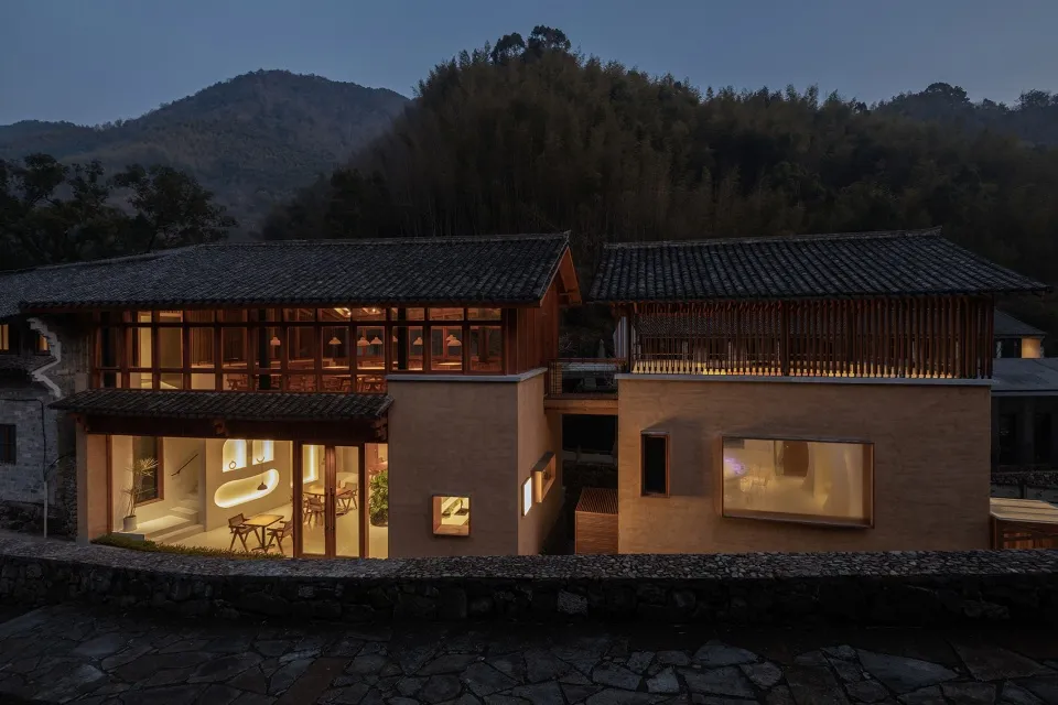 Asian-style house with a large wooden structure, stone roof, and multiple rooms, including a dining area with chairs and potted plants