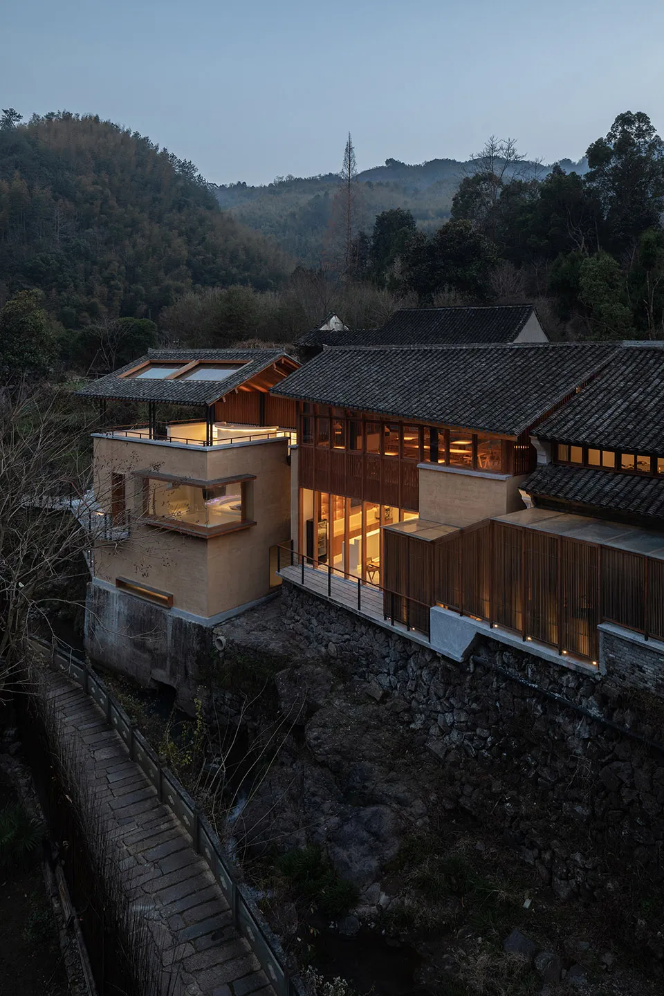 木質外觀的亞洲風格住宅，位於山坡上俯瞰河流，大片開放空間通往露台，並有多扇窗戶引入自然光線