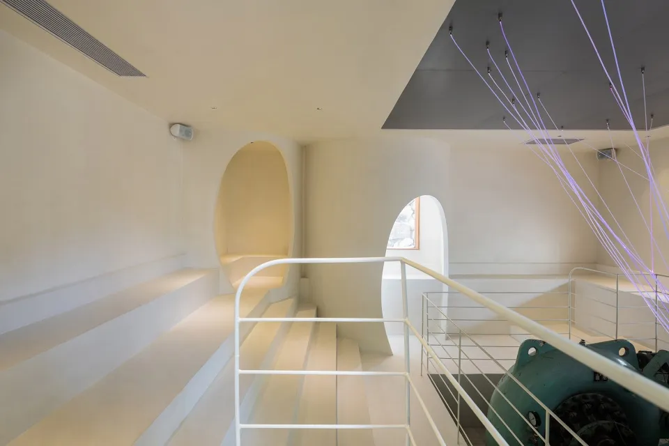 Open modern space with white walls, a circular window, and two sets of stairs
