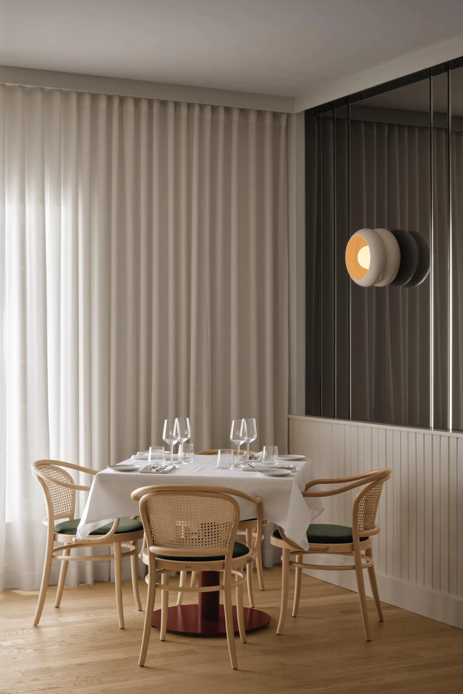 A formal dining area with a large white table surrounded by chairs, wine glasses, and a clean, organized atmosphere