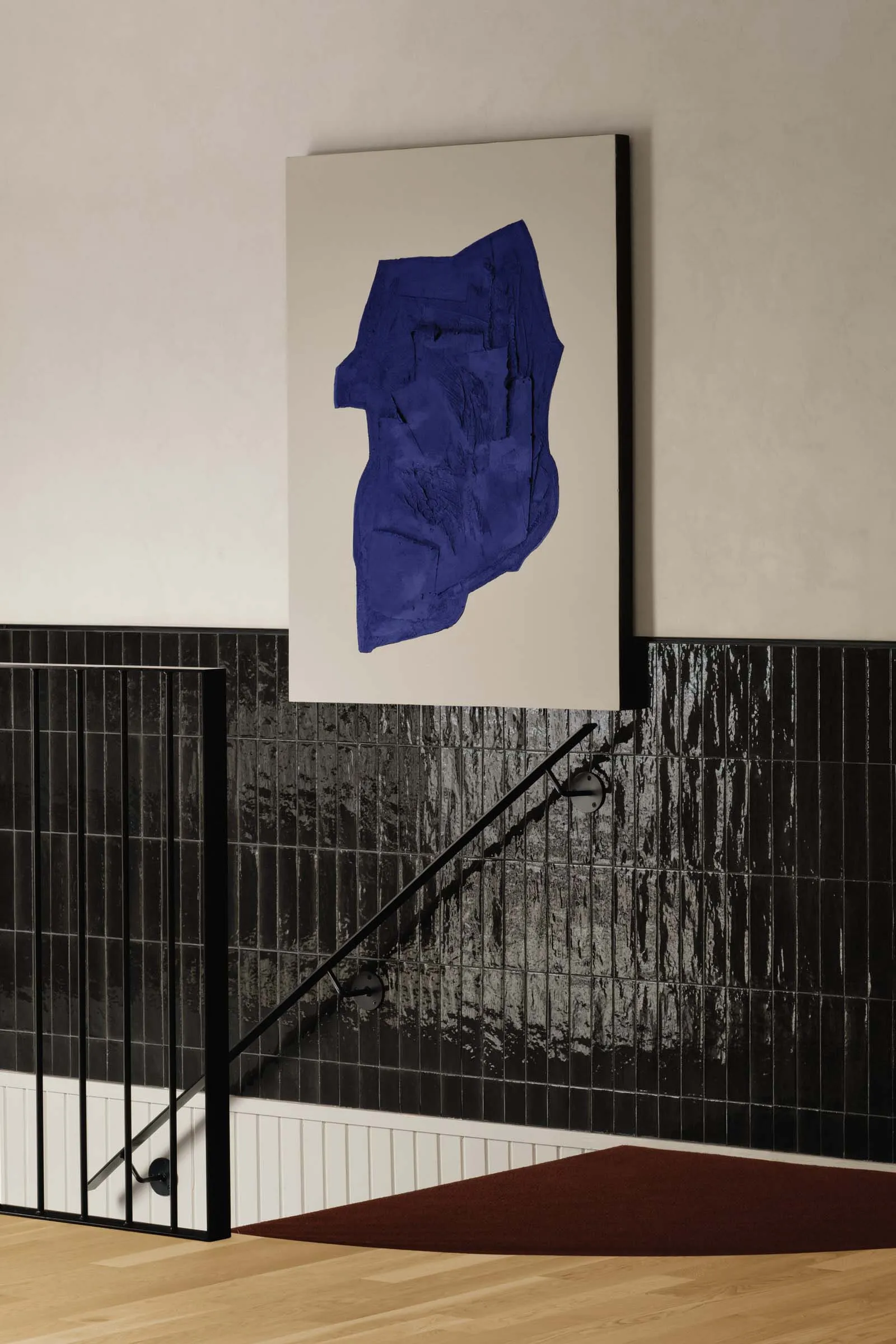 A modern staircase with black steps and a large blue painting above, creating a striking contrast in a contemporary space