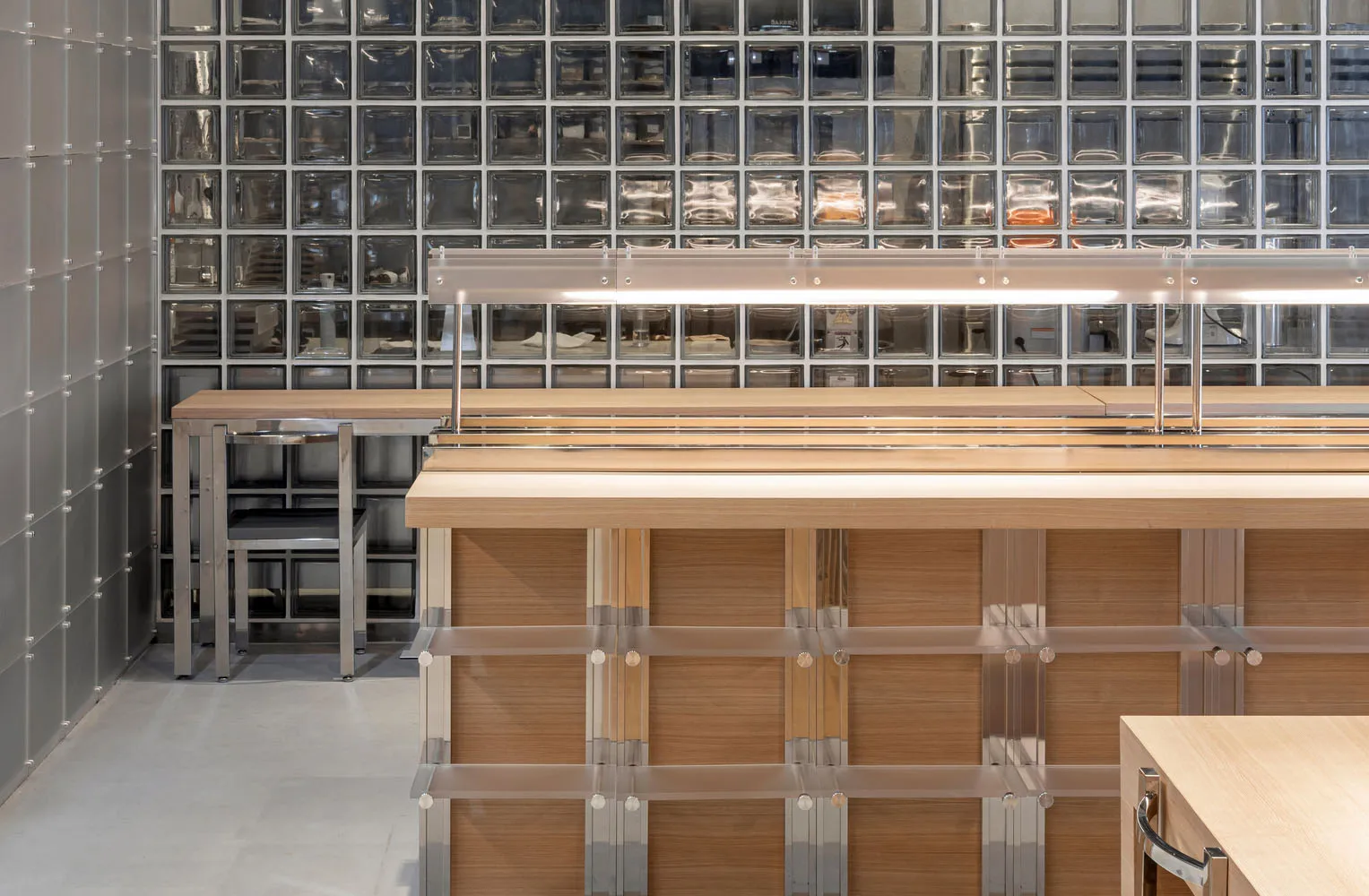 A modern restaurant interior with a wooden counter, chairs, and a light fixture, creating a comfortable dining atmosphere