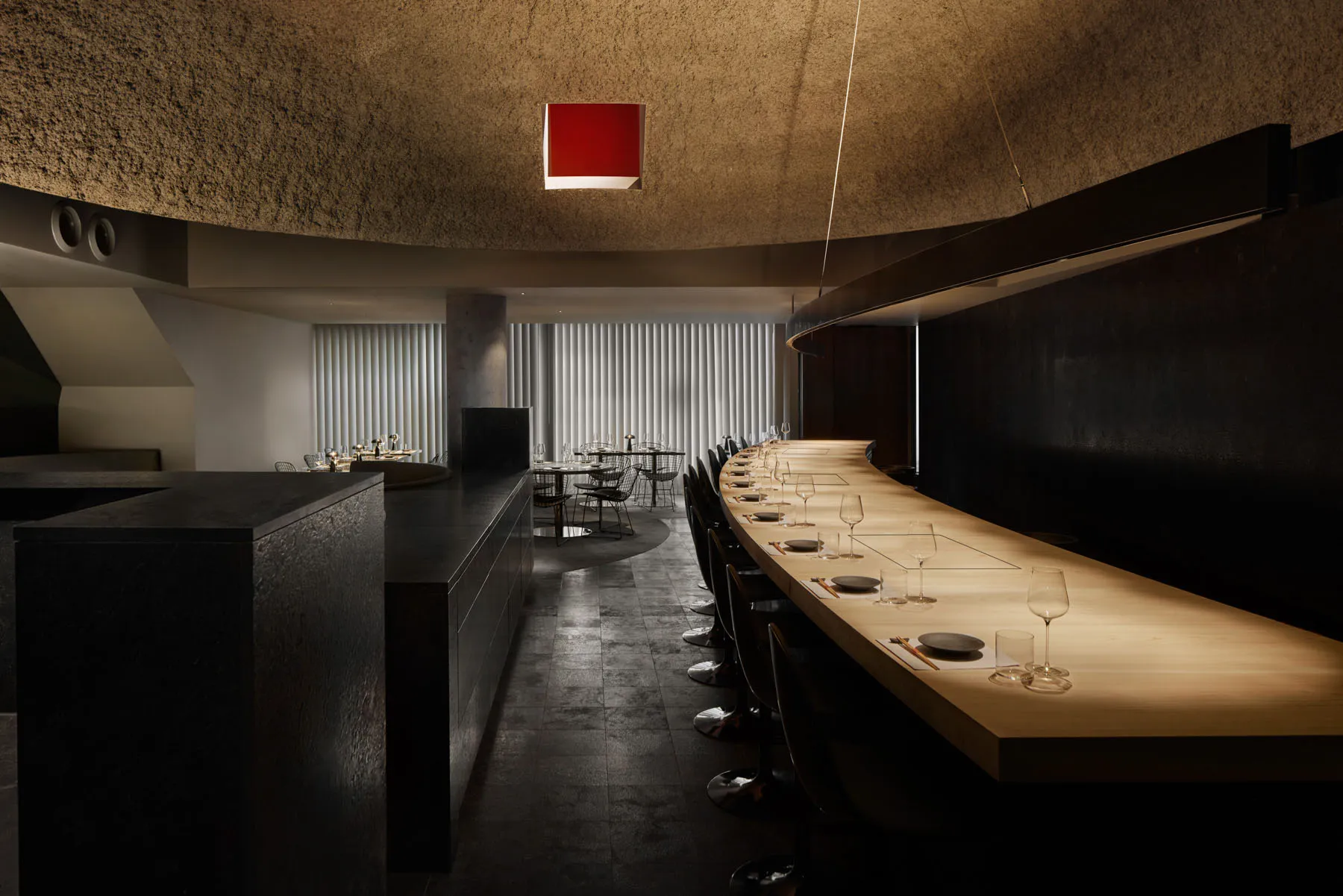 現代餐廳內部，長形木質餐桌環繞黑色座椅、酒杯與高級氛圍