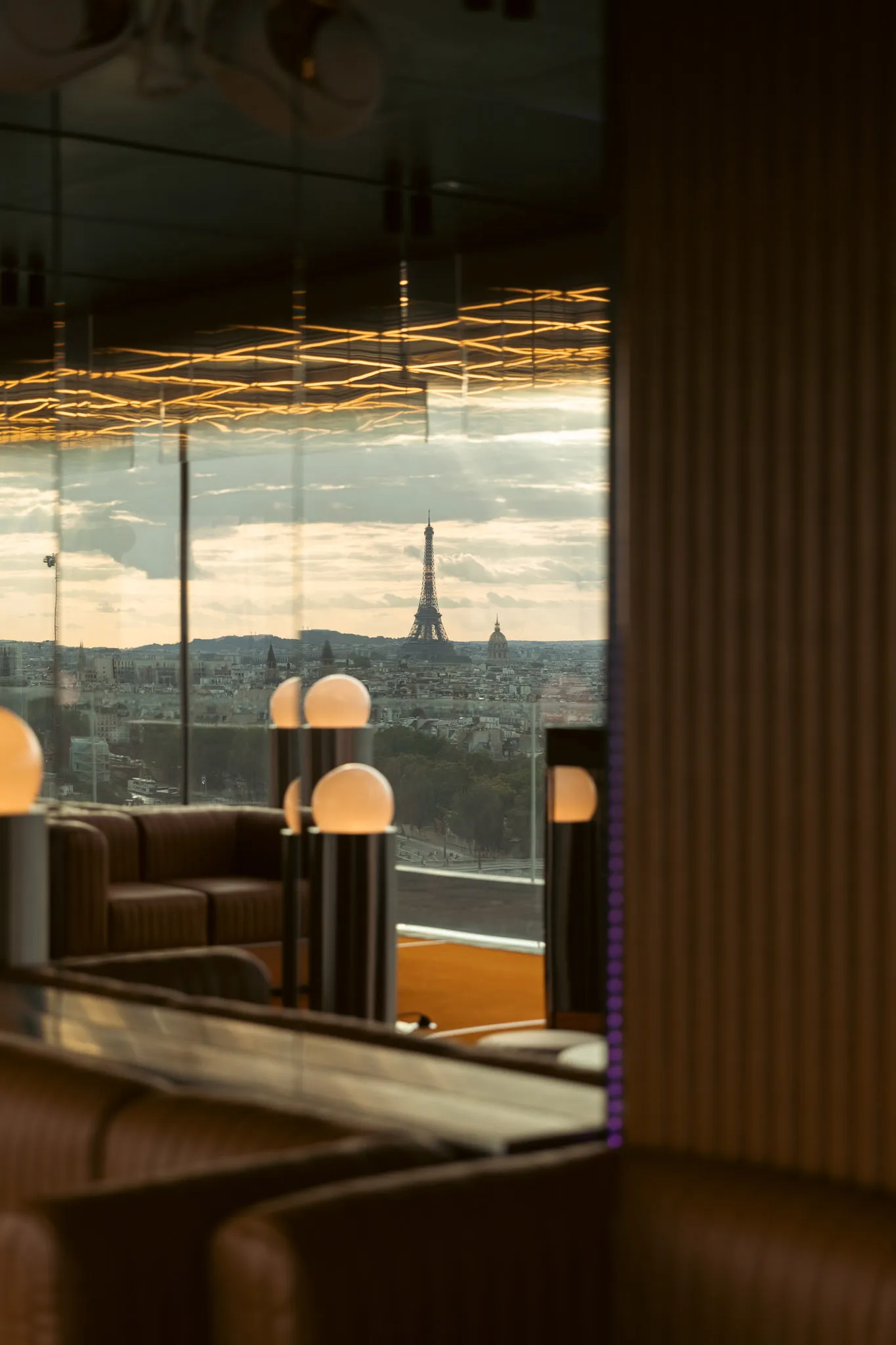 Cozy Parisian cafe with a large dining area, multiple lamps, and a view of the Eiffel Tower outside