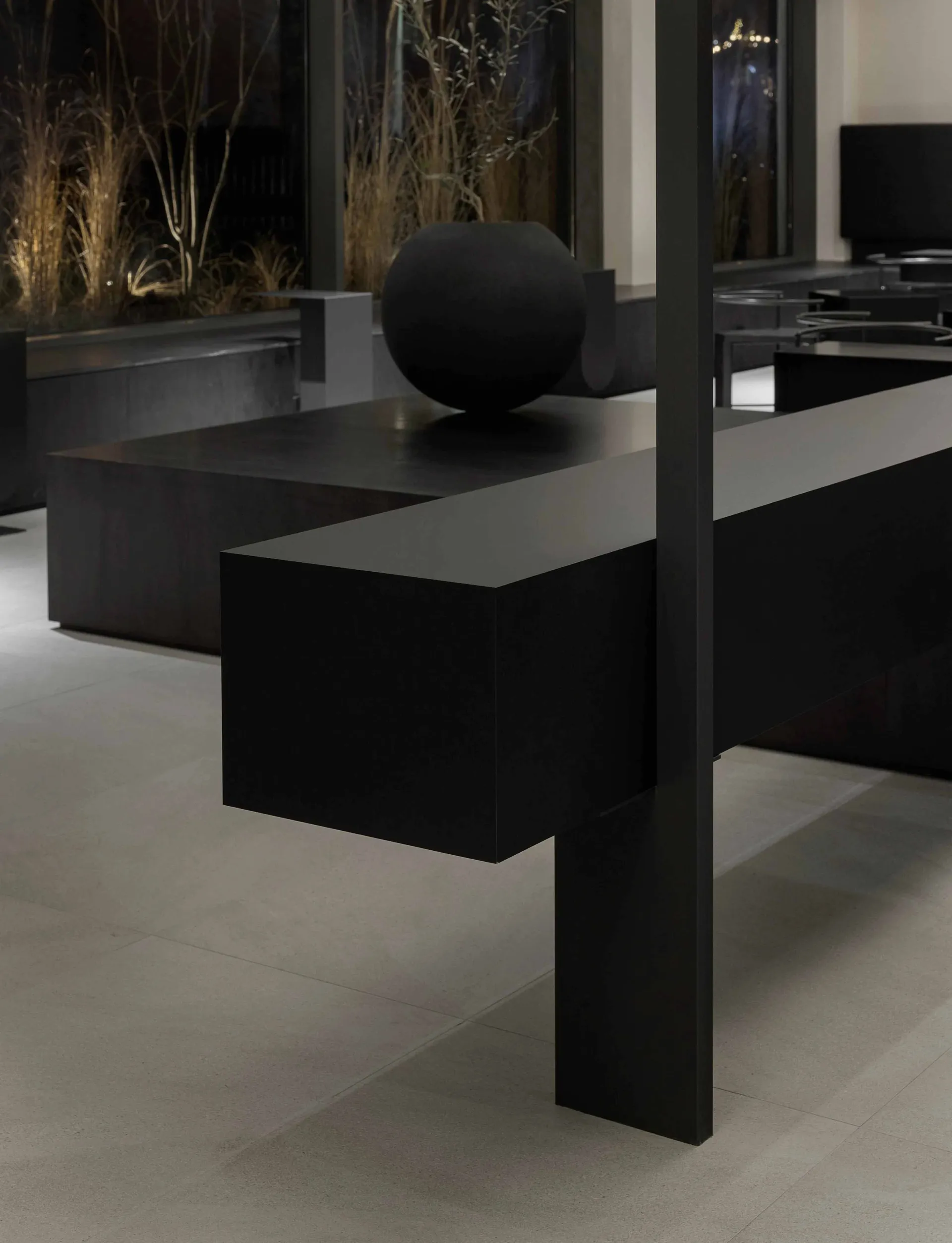 Modern room with a black table, sphere, and benches, featuring a chair and a large window